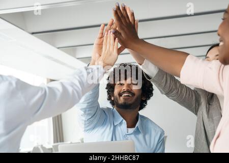 Ein glückliches, vielfältiges, multiethnisches Geschäftsteam, das mit fünf hochgehogenen Händen aufsteht Stockfoto