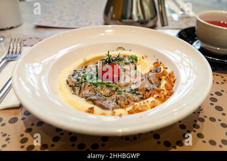 Traditionelles Rindfleisch Stroganoff in einer Keramikschale mit Kartoffelpüree auf einem Tisch in einem Restaurant mit selektivem Fokus Stockfoto