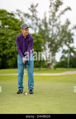 Mann spielt Golf und lächelt Stockfoto