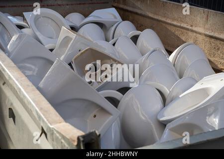 Entfernt Alte gebrauchte Keramik-Toilettenschüsseln liegen im Abfallbehälter in Heap für das Recycling. Bauabfall Stockfoto