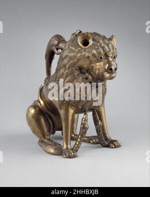 Aquamanile in Form eines Löwen ca. 1230 oder Anfang des 19. Jahrhunderts Norddeutsch, Lübeck (?) Ein Aquamanil, aus dem lateinischen Wort für Wasser (aqua) und Hand (manus), ist ein Gefäß, das sowohl im religiösen als auch im weltlichen Kontext zum Ritual des Händewaschens verwendet wird – vom Priester vor der Messe und in einem Privathaushalt vor dem Essen. Überlebende mittelalterliche Beispiele wurden in Kupferlegierung in Form von Tieren oder Figuren gegossen. Dieser kauzende Löwe könnte im frühen dreizehnten Jahrhundert in Deutschland hergestellt worden sein, obwohl einige technische Aspekte auf ein viel späteres Datum hinweisen. So kann es ein Beispiel für eine mittelalterliche Wiederbelebung sein Stockfoto