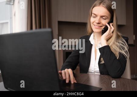 Geschäftskonzept. Nahaufnahme, junge lächelnde Geschäftsfrau im Heimbüro, die am Handy spricht, Telearbeit und freiberufliche Frau, die zu Hause arbeitet Stockfoto