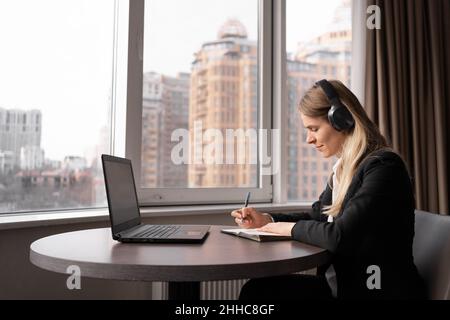 Fokussierte Millennials-Frau, die im hellen, gemütlichen Heimbüro fern arbeitet, Erwachsene Studentin, die online studiert, Geschäftsfrau, Videokonferenz mit Kopfhörern Stockfoto