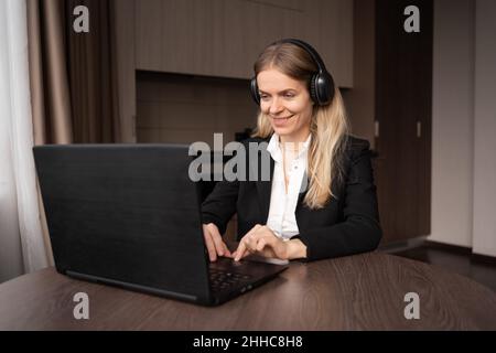 Remote-Work-Konzept. Kaukasische Frau mit Kopfhörern arbeitet ferngesteuert auf ihrem Laptop, Freiberuflerin oder Lehrerin hat eine Videoanruf-Beratung, Millennial Girl Stockfoto
