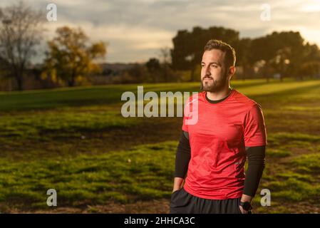 Selbstbewusster Sportler, der bei Sonnenuntergang im Park Musik hört Stockfoto