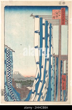 Dye House in Konya-Cho, Kanda 1857 Utagawa Hiroshige Japanisch zu Hiroshiges Zeit konnte jeder, der Edo kannte, die drei bekanntesten Wahrzeichen der Stadt erkennen: Den entfernten Berg Fuji, das Schloss Chiyoda und die Nihon-Brücke. So lässt die Einbeziehung des Schlosses im Stadtbild und des Fuji-Berges am Horizont keinen Zweifel daran, dass es sich um eine Edo-Szene handelt. Aber während diese Merkmale in Darstellungen der Hauptstadt de rigueur waren, war Hiroshiges Innovation, den Standpunkt inmitten der windgeblasenen Textilien der Trockenplattform eines Färbers zu positionieren. Er sieht Edo aus Konya-Cho, einer Straße im Schlepptau der Handwerker Stockfoto