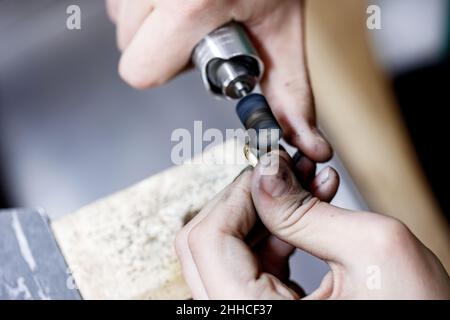 Nahaufnahme Hände des Handwerkers Juwelier Polieren einer goldenen Ring-Oberfläche mit Schleifmaschine. Der Goldschmied arbeitet gerade. Stockfoto