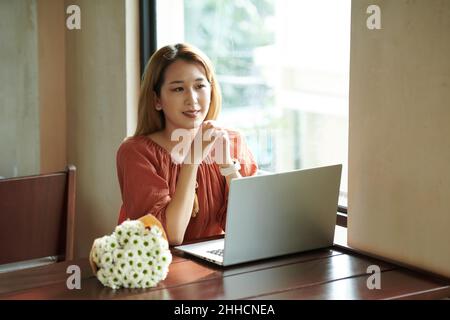 Lächelnde junge Frau, die am Kaffeetisch am Laptop arbeitet Stockfoto