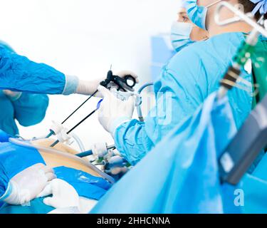 Chirurgen im Team arbeiten im Operationssaal mit modernen laparoskopischen Instrumenten. Selektiver Fokus auf die Hände des Arztes. Laparoskopische Chirurgie. Krankenhaushintergrund. Stockfoto