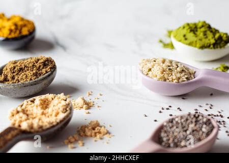 Superfood-Pulver in Löffeln, weißer Marmorhintergrund, Kopierraum. Stockfoto