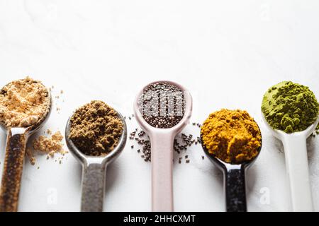 Superfood-Pulver in Löffeln, weißer Marmorhintergrund, Kopierraum. Stockfoto