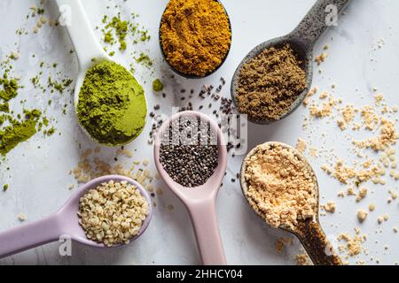 Flache Lage von Superfood-Pulvern in Löffeln, weißer Marmorhintergrund. Stockfoto