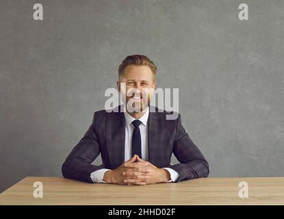 Lächelnder kaukasischer Geschäftsmann, der am Schreibtisch sitzt und auf das Fotostudio schaut Stockfoto