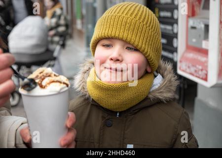 Kleiner Junge, der draußen Karamelllatte füttert Stockfoto