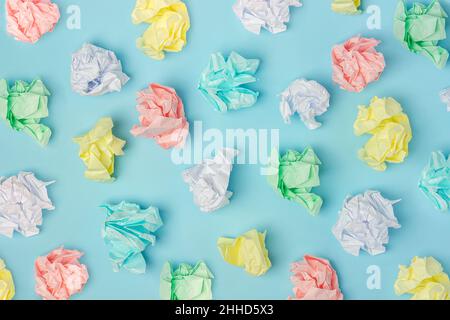 Muster mit farbigen zerknitterten Papierkugeln auf blauem Hintergrund, Textur. Draufsicht Flat Lay. Stockfoto