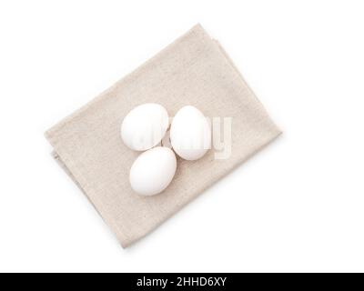 Drei Hühnereier auf Küchentuch, isoliert auf weiß, Draufsicht Stockfoto