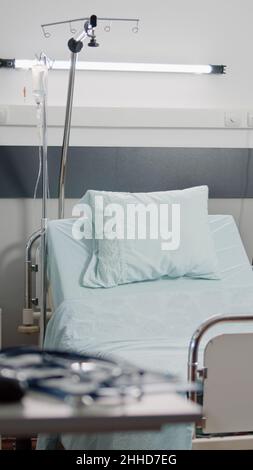 Leeres Bett auf der Krankenhausstation mit medizinischen Geräten für die Gesundheitsversorgung und Erholung. Niemand im Reanimationsraum mit Herzfrequenzsensor und Infusionsbeutel für Intensivpflege und Hilfe. Stockfoto