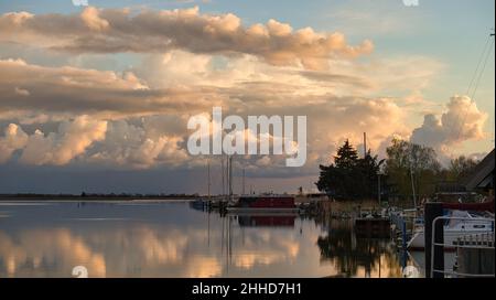 Der Bodden bei Zingst an der Ostsee in den Abendstunden. Boote liegen auf dem Steg die Wolken spiegeln sich im ruhigen Wasser. Stockfoto