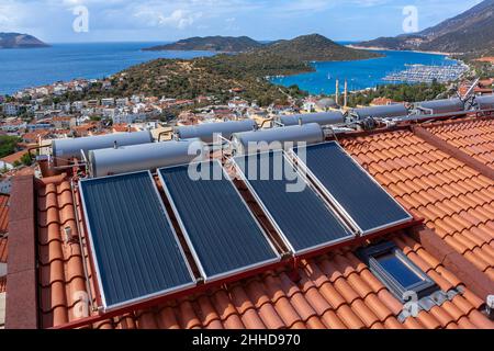 Solar-Warmwasserbereiter auf Fliesendach des Hauses für die wirtschaftliche Erwärmung von Wasser installiert. Viele große Wassertanks. Stockfoto