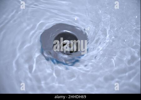 Wasser fließt durch das Loch in einem Spülbecken. Stockfoto