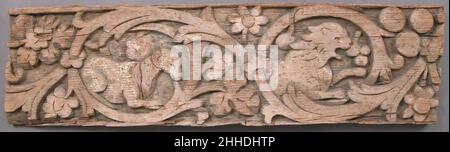 Relief Frieze 6th Century Coptic Ein Löwe und ein Leopard sprinten in die Mitte dieses hölzernen Sturzes, während andere Tiere friedlich sitzen. Paradiesische Pfauen bewachen eine gemmierte Kreuzung zwischen wabenden Vorhängen, drapiert und hinter zwei Säulen gehalten. Ein durchgehender, dekorativer Stiel aus Reben, Blumen und Trauben umkreist die Tiere in sechs Medaillons und kreiert ein Motiv, das als Rinceau bekannt ist. Die ursprünglichen hellen Blau-, Pink- und Grüntöne hätten die Dekoration des Sturzes belebt. Der Künstler verschmolz klassische Motive, die typischerweise Wohlstand mit christlichen Themen repräsentieren würden, möglicherweise illustriert Stockfoto
