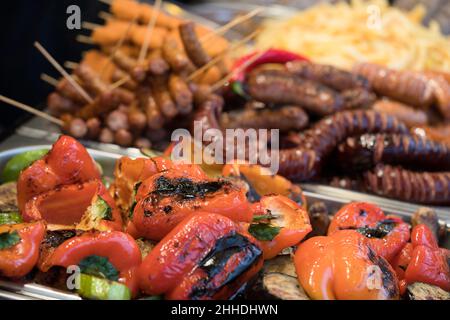 Frische leckere gegrillte und gebratene bayerische Würstchen, Gemüse und andere Speisen mit Stöcken. Street Food auf dem lokalen Markt des traditionellen Festivals, stree Stockfoto