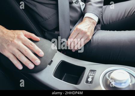 Ein Mann in einem Business-Anzug befestigt ein Auto-Sicherheitsgurt Foto aus nächster Nähe Stockfoto