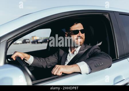 Geschäftsmann in schwarzer Brille sitzt hinter dem Steuer eines Autos Stockfoto