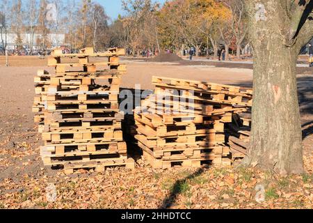 Stapel von groben Holzpaletten im Lager im Herbstpark an sonnigen Tagen. Palettenlagerung Fracht- und Versandkonzept. Stockfoto