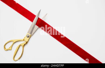 Große Öffnung, Bandschnitt, Goldschere schneidet rotes Samtband isoliert auf weißem Hintergrund. Einladung zur Eröffnung, Konzept zur Unternehmenseinführung, Kopie en Stockfoto