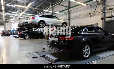 Minsk, Weißrussland - 05. Jan 2022: Innenraum der Autowerkstatt mit Autos auf dem Aufzug Stockfoto