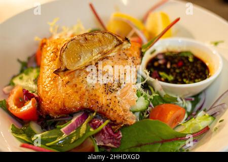 Im Ofen gebackenes Lachsfilet mit Chili und Sojasoße, serviert auf einer Oberseite des gemischten Salats. Stockfoto