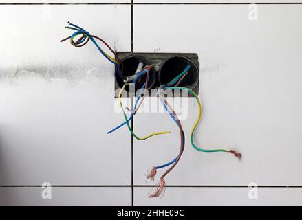 Aus der Wand hervorstehende elektrische Drähte Stockfoto