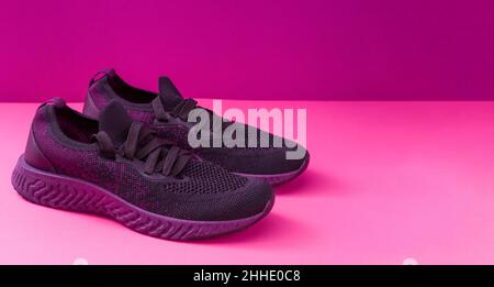 Sneakers-Konzept mit Platz für Text. Nahaufnahme von rosa Sneakers auf hellem Hintergrund. Sportschuhe für Laufen und Fitness. Paar Schuhe. Aktiver Lebensstil. Textur mit lila Sohle und Schnürsenkeln. Stockfoto