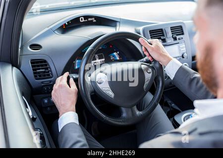 Im Innenraum des Autos schaltet der Mann den Lichtmodus und schaltet den Turn ein Stockfoto