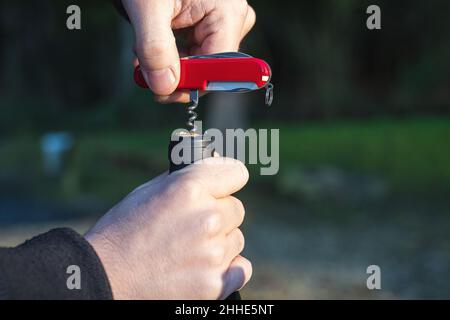 Öffnen einer Weinflasche mit einem Taschenmesser Korkenzieher Stockfoto