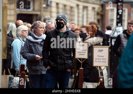 Ein junges Paar mit Gesichtsmasken wartet darauf, als Schlange vor Bettys Cafe und Tea Rooms in der Stadt York in North Yorkshire als Gastfreundlichkeit sitzen zu können Stockfoto