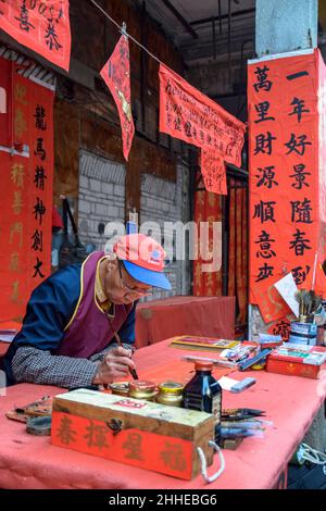 Foshan, Provinz Guangdong, China. JANUAR 14, 2022. Menschen, die Couplets mit Grüßen für das Frühlingsfest schreiben. Vorbereitung auf das chinesische Neujahr Stockfoto