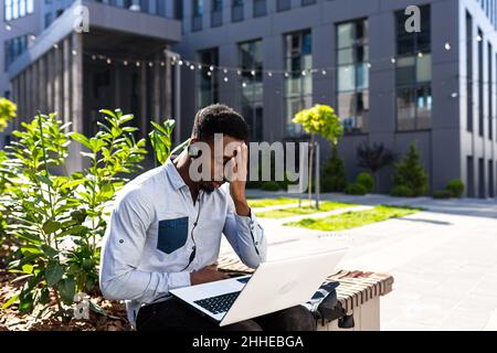 Müde afroamerikanischen Geschäftsmann arbeiten auf Laptop im Park auf der Bank, frustrierter Mann Stockfoto