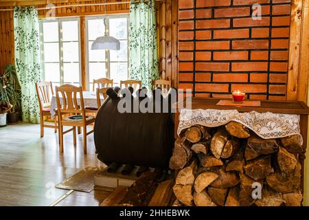 Bullerjan Haus Holzofen Heizgerät in Holz Ferienhaus Haus Interieur, mit Stapel von Brennholz daneben. Stockfoto