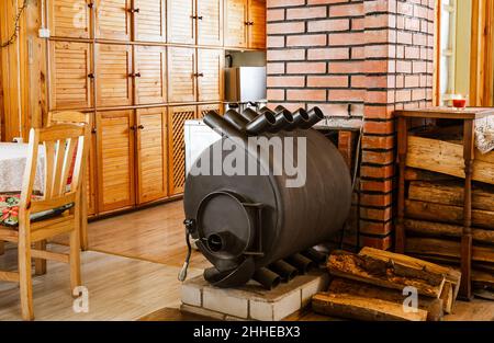 Bullerjan Haus Holzofen Heizgerät in Holz Ferienhaus Haus Interieur, mit Stapel von Brennholz daneben. Stockfoto