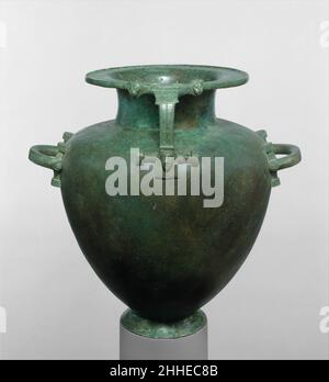 Bronzehydria (Wasserkrug) Ende 7th–Anfang 6th Jahrhundert v. Chr. Griechisch Dies ist eine der frühesten dieser Art von archaisch-griechischen Bronzehydrien, die überlebt haben. Die Griffe sind gegossen. Teile des gehämmerten Bronzenkörpers sind eine moderne Restaurierung. Die drei Griffe sind besonders dekorativ, besonders für diese frühe Periode. Der vertikale Griff hat oben ein Paar Löwenköpfe, deren Merkmale mit einer Kombination aus volumetrischer Modellierung und Jagd gerendert werden. Unten erscheint der Kopf einer Frau, der vom Hals nach oben zeigt. Sechs lange, geschlüpfte Zöpfe umrahmen ihr Gesicht auf beiden Seiten und sie trägt einen Kopfbedeckung Stockfoto