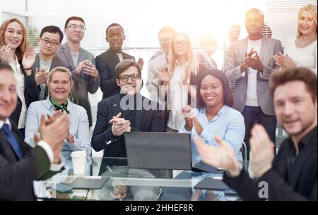 Multinationale Arbeitsgruppe feiert gemeinsam in der Nähe des Desktops. Stockfoto