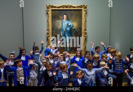 The National Gallery, London, Großbritannien. 24. Januar 2022. ‘The Blue Boy’, 1770, von Thomas Gainsborough wird zum 100th. Jahrestag seiner letzten Präsentation in Großbritannien in der National Gallery ausgestellt. Das Werk ist heute im Besitz der Huntington Library, des Art Museums und des Botanischen Gartens in San Marino, Kalifornien, wo es seit dem letzten Jahrhundert ausgestellt wird. Eine Gruppe ‘blauer Jungen’, Kinder von Mitarbeitern der National Gallery und der US-Botschaft in London, posieren vor dem Gemälde, alle in Blautönen gekleidet mit Kravatten, die der Figur auf dem Gemälde ähneln. Quelle: Malcolm Park/Alamy Live News. Stockfoto