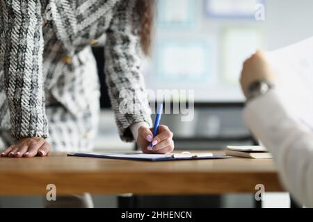 Frau im Büro unterschreibt Dokumente, Nahaufnahme Stockfoto
