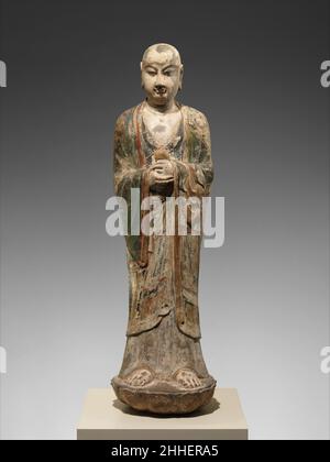 Mönch, wahrscheinlich Ananda (Anantuo) 8th. Jahrhundert China dieser junge Mönch, höchstwahrscheinlich Ananda, war einst Teil einer großen Gruppe, zu der ein Buddha in Begleitung von Bodhisattvas und Hütern gehört hätte. Die Figur enthält ein nicht identifizierbares Objekt, das ein in einem roten Tuch gewickeltes Opfer darstellen kann. Nach dem sechsten Jahrhundert wurde Buddha Shakyamuni oft mit zwei Schülern dargestellt – dem jungen Ananda und einem älteren Mönch, Kashyapa, der für seine übernatürlichen Kräfte bekannt war. Ananda, Shakyamunis Cousin, diente als Buddhas persönlicher Begleiter und war bekannt für seine ungeheisame Erinnerung. Er war auch ein cham Stockfoto