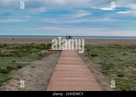 Strandpromenade zum Meer mit einer Gruppe von Teenagern, die am Ende stehen, Garrucha, Provinz Almeria, Andalucía, Spanien Stockfoto