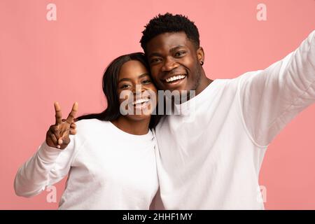 Nahaufnahme Porträt von fröhlichen schwarzen Paar unter Selfie auf rosa Stockfoto