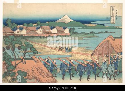 Fuji in der Entfernung vom Senju Pleasure Quarter (Senju kagai yori chōbō no Fuji), aus der Serie sechsunddreißig Ansichten des Mount Fuji (Fugaku sanjūrokkei) ca. 1830–32 Katsushika Hokusai Japanese Eine Prozession von Männern, die in blau und grün gekleidet sind und rote Musketen tragen, verlässt die Hauptstadt in ihre Heimatprovinz. Der Mann links, die Hand zur Stirn erhoben, reflektiert zweifellos die zurückgelassenen Freuden. Fuji erscheint am Horizont und wacht über die Prozession von daimyō. Fuji in der Entfernung vom Senju Pleasure Quarter (Senju kagai yori chōbō no Fuji), aus der Serie sechsunddreißig V Stockfoto