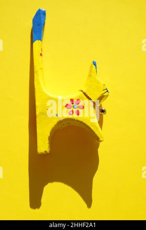 Gelbe hölzerne Katzenfigur auf sonnigem gelbem Tisch. Stockfoto